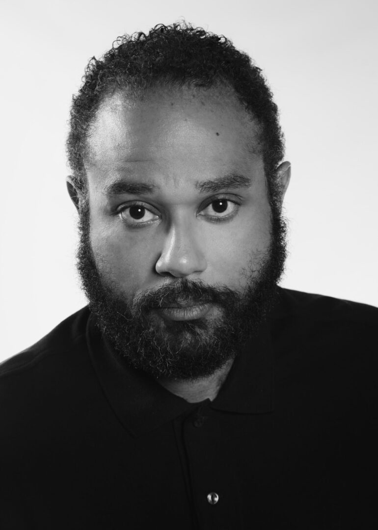 A black and white photo of a man with beard.